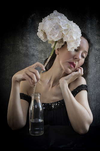 woman in black sequin dress holding with her right hand a large hortensia VI