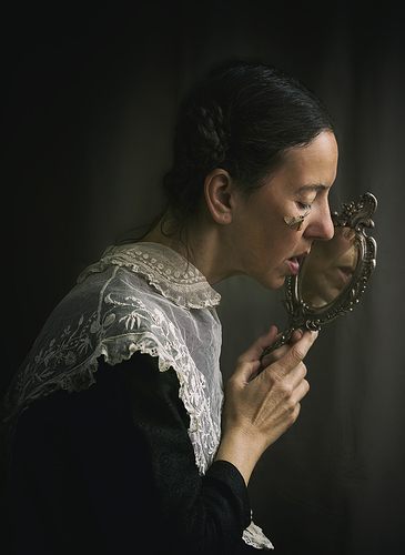 woman with antique embroidered collar on black dress in romantic attitude with a moth in her face IX