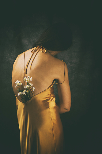 woman from behind with yellow satin dress and flowers on her back